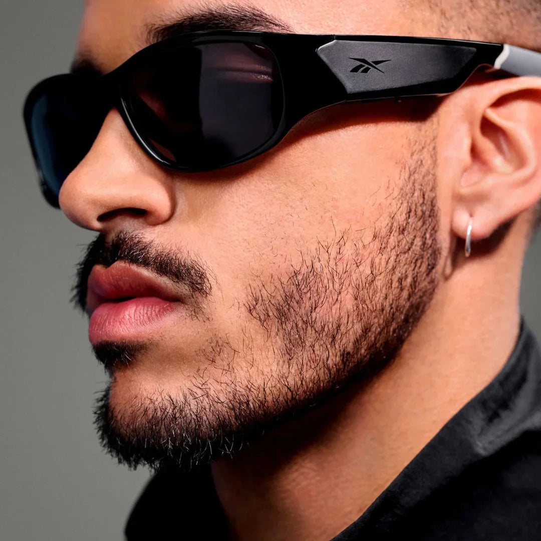 Primer plano de hombre usando gafas Ray-Ban Meta deportivas; enfoque en el altavoz y la cámara lateral para interacción con IA.
