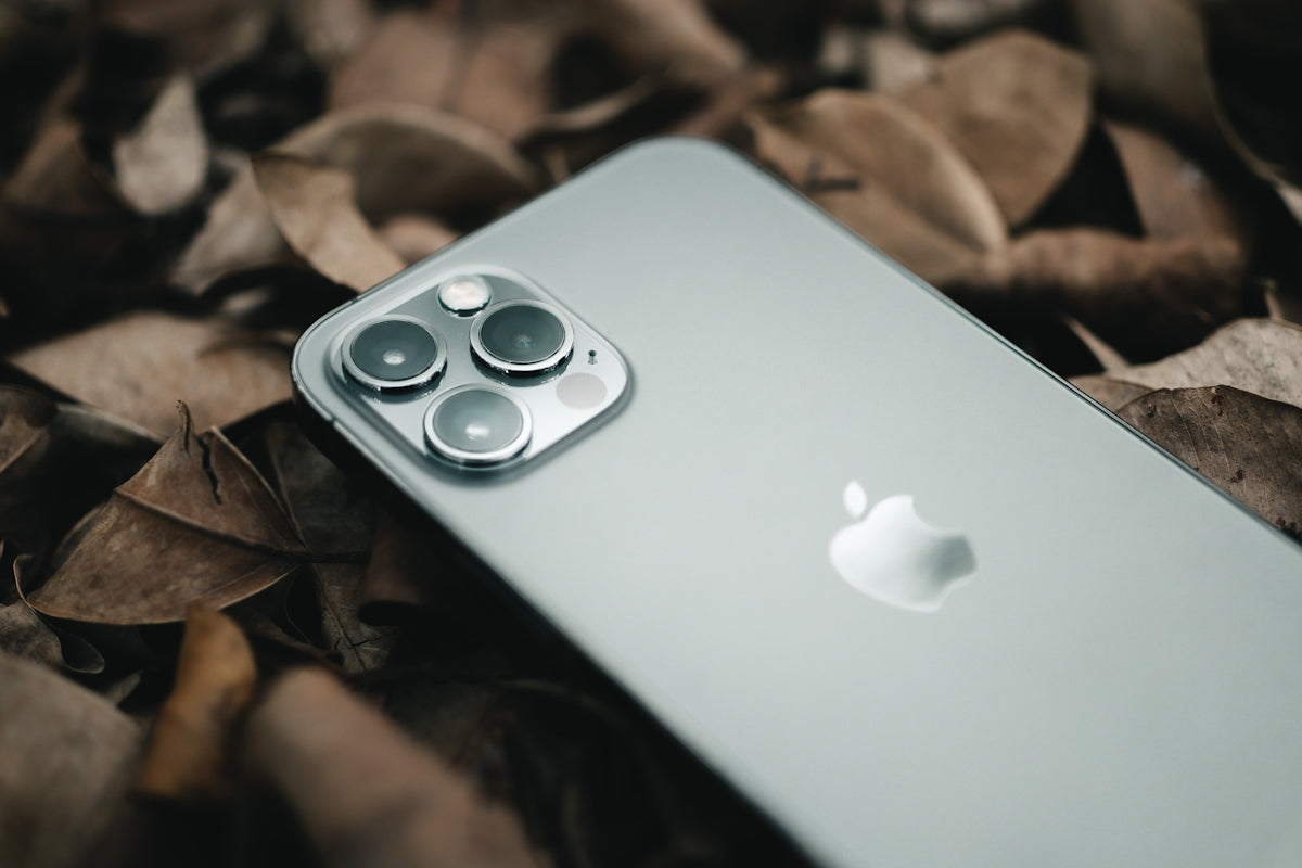 a close up of an iphone on a bed of leaves